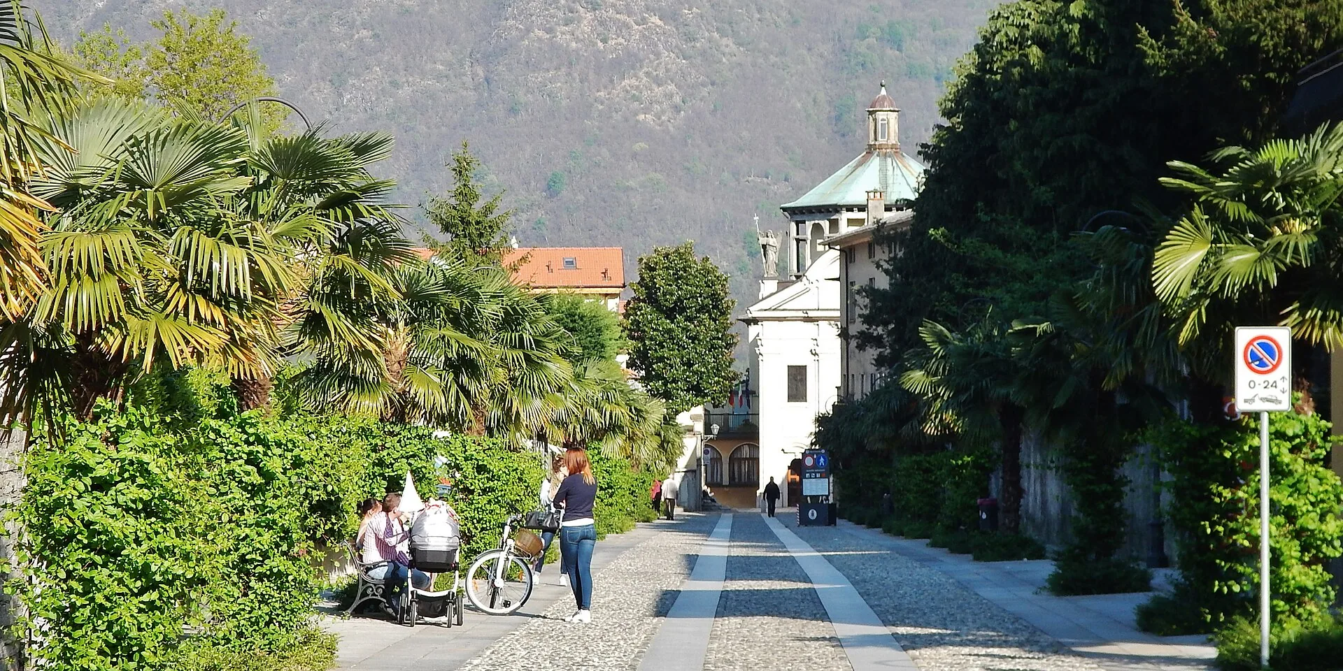 Una passeggiata alberata di Cannobio con le palme e la cupola del santuario